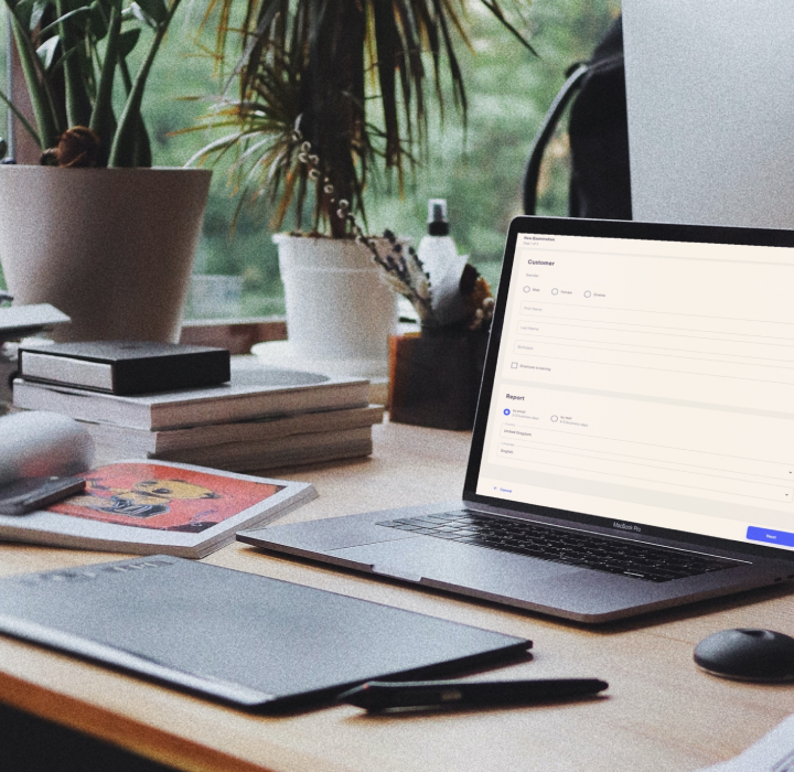 A laptop on a desk, surrounded by books and desk-flowers, displaying a part of an app developed for a client.