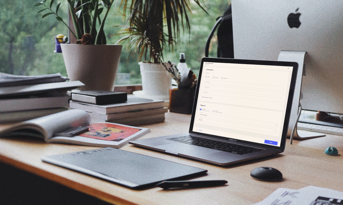 A laptop on a desk, surrounded by books and desk-flowers, displaying a part of an app developed for a client.